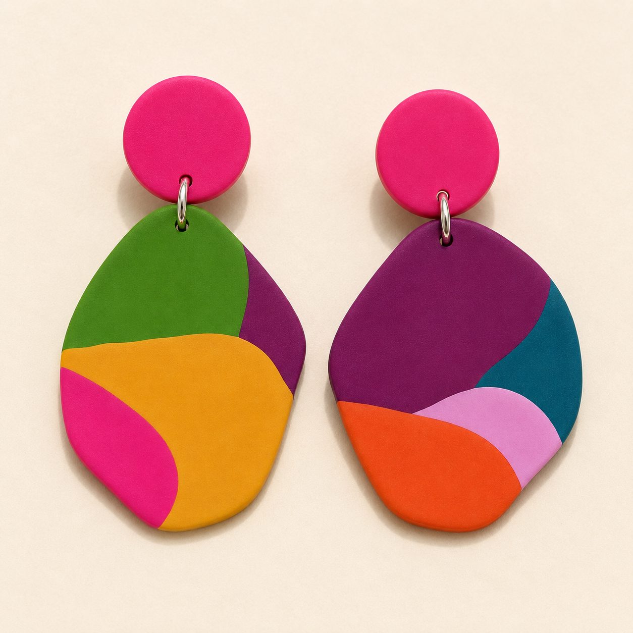 Handmade earrings in magenta, orange, green, teal, and purple on a cream ground